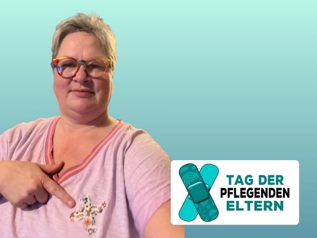 Das Bild zeigt Birgit Beutler, pflegende Mutter und Vorstandsmitglied im Verein wir pflegen in Niedersachsen e.V. Sie trägt ein rosa T-Shirt auf dem zwei gekreuzte Pflaster kleben. Die Pflaster sind das Symbol für den Tag der pflegenden Eltern. 
